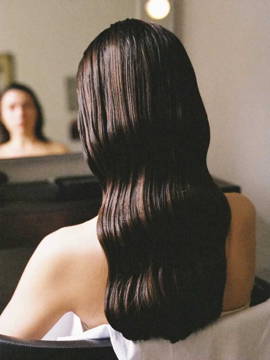 A finished blow-dry, seen from behind, long dark hair in soft waves