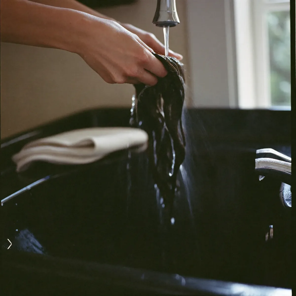 At the backwash, a hand rinsing water through wet hair