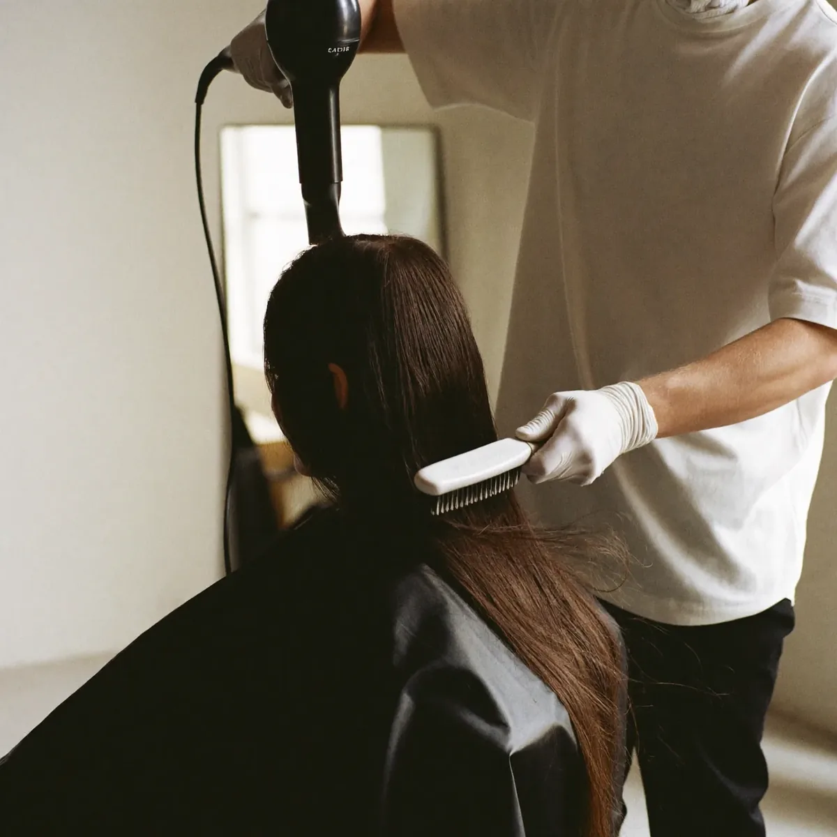 A stylist mid blow-dry, working a round brush through a client's hair
