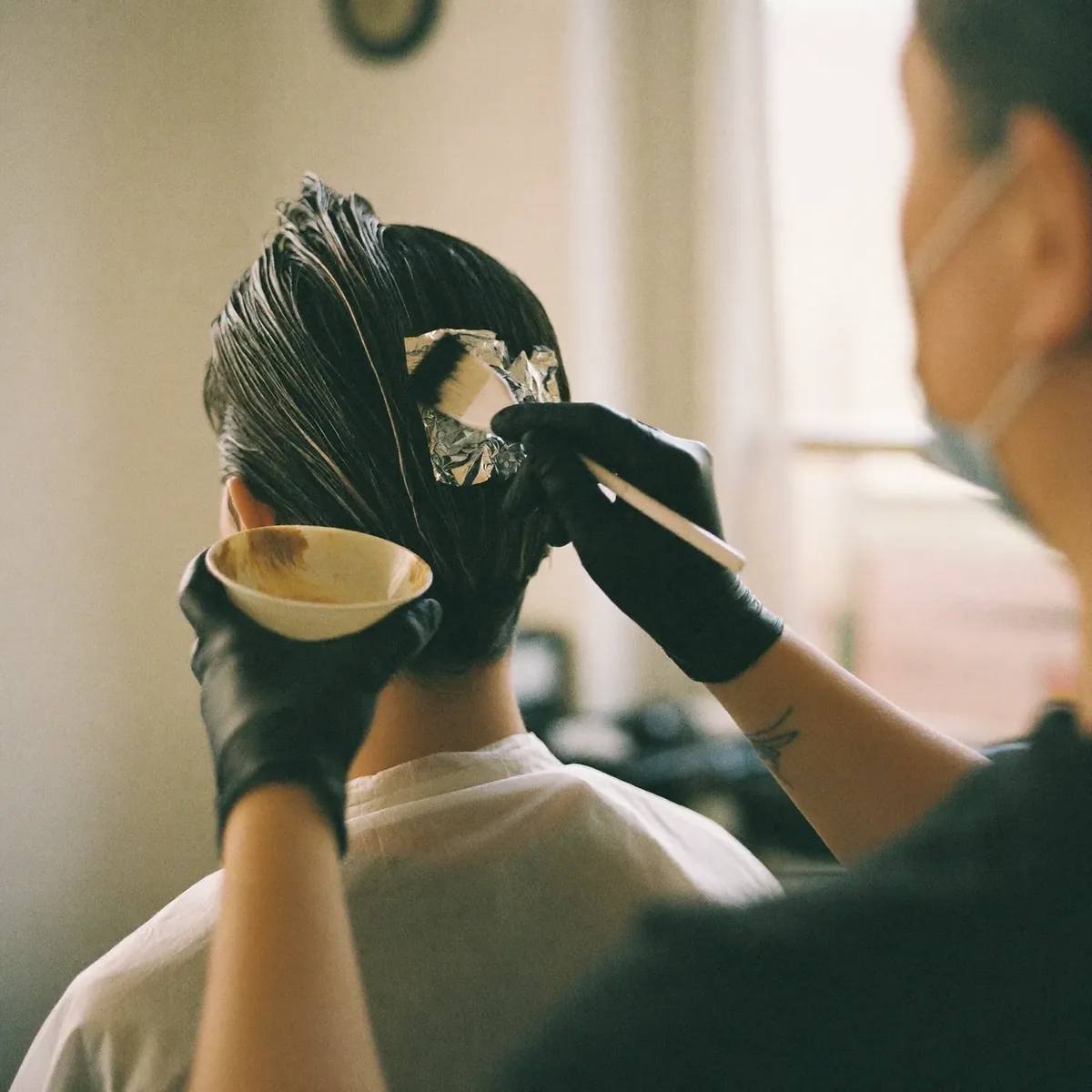 Colour being applied to sectioned hair with a tint brush